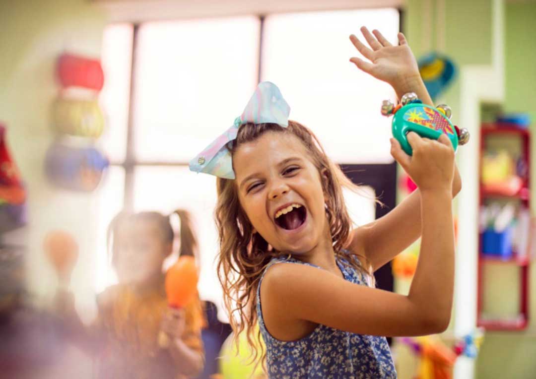 criança feliz brincando com pandeiro infantil