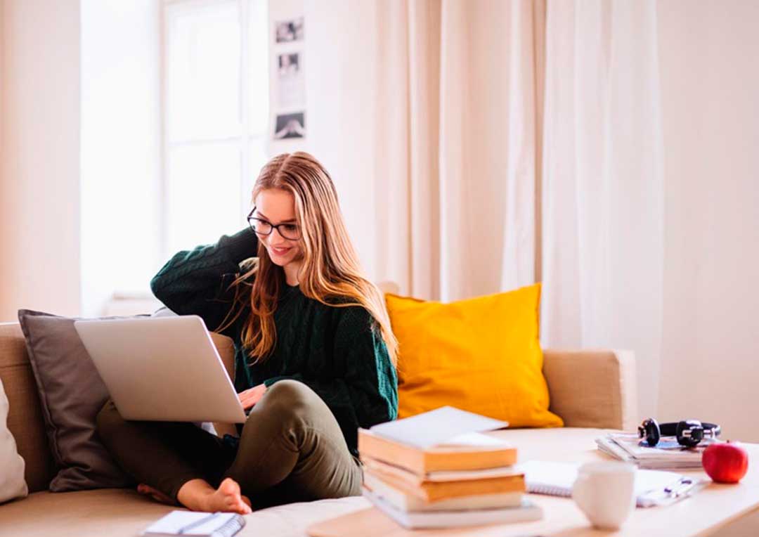 menina sorrindo sentada no sofá olhando para notebook