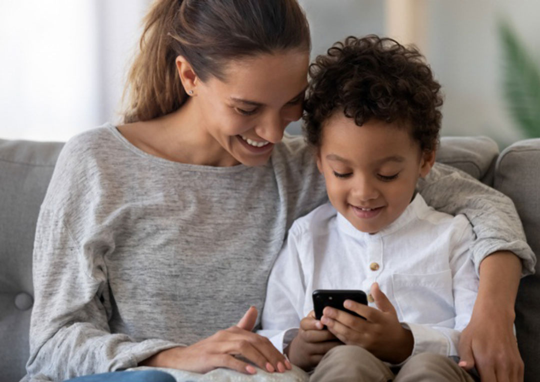 mãe e filho sentados juntos no sofá e olhando para um celular