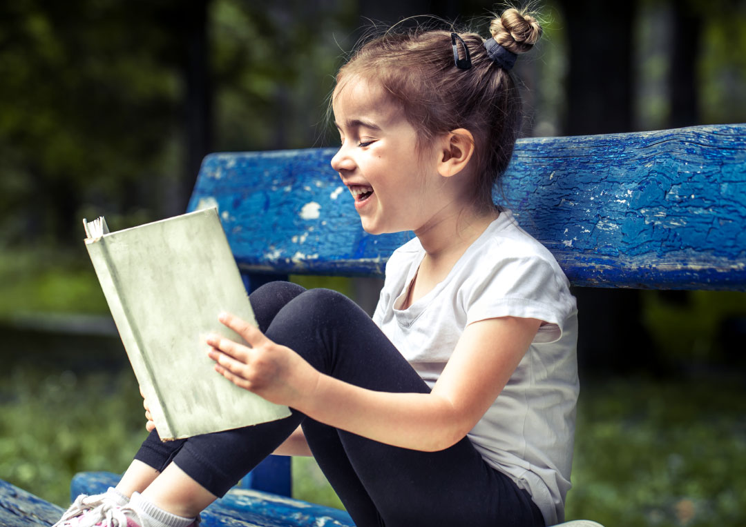 menina sorrindo lendo um livro