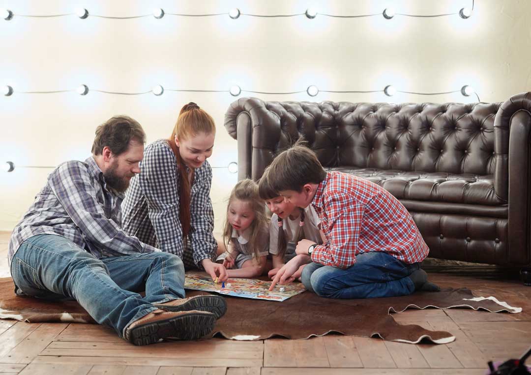 pai e mãe jogando jogo de tabuleiro com três filhos