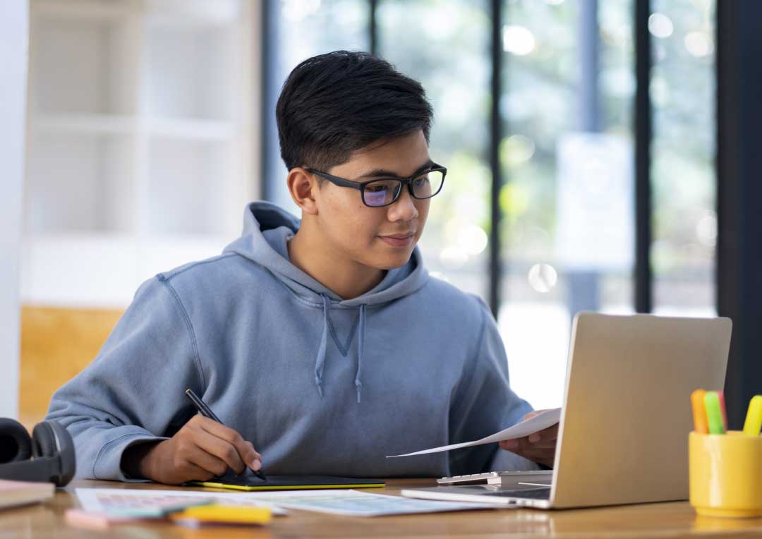 menino sentado e usando computador para estudar