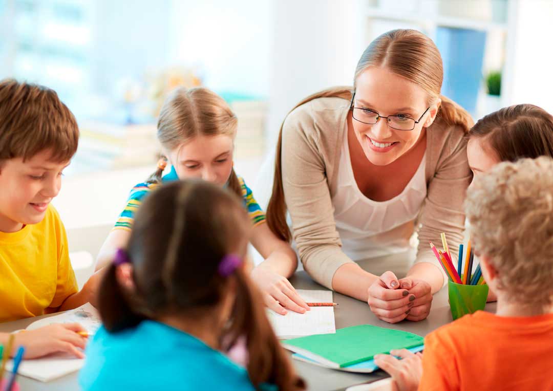 professora sorrindo com grupo de alunos e estudando