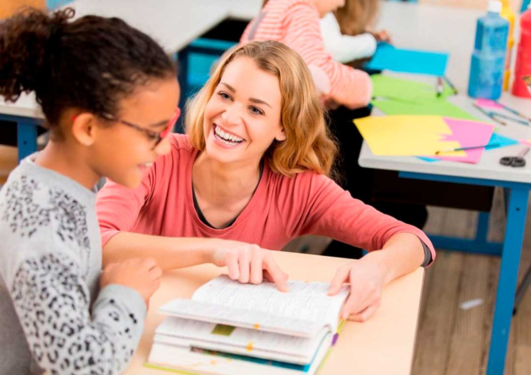 professora sorrindo com aluna em sala de aula